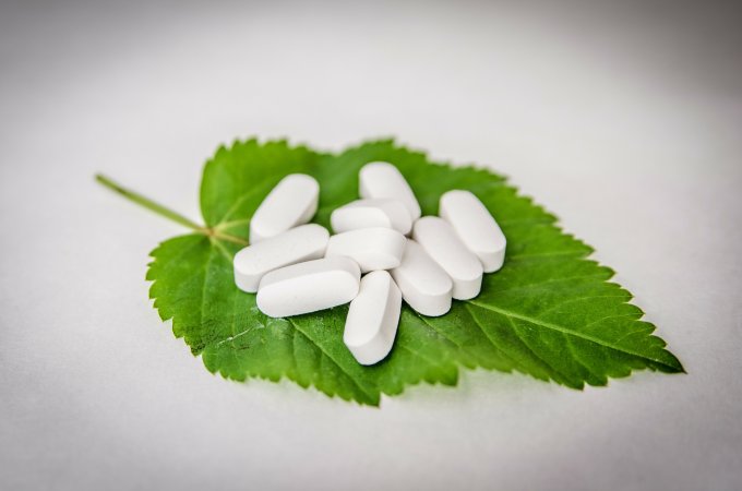Białe tabletki magnezu na zielonym liściu