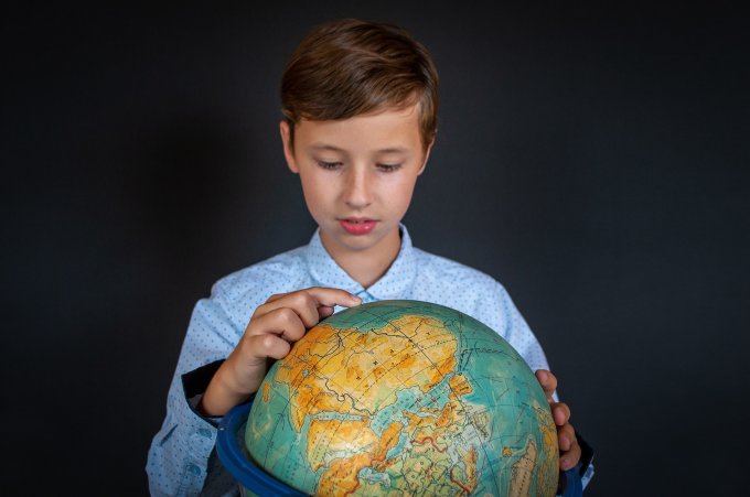 Chłopiec uczy się mapy świata wykorzystując globus