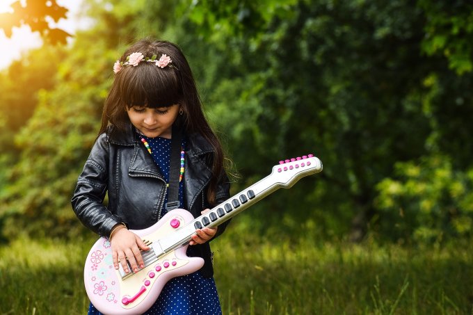 Dziewczynka uczy się grać na gitarze, rozwijając swoje umiejętności
